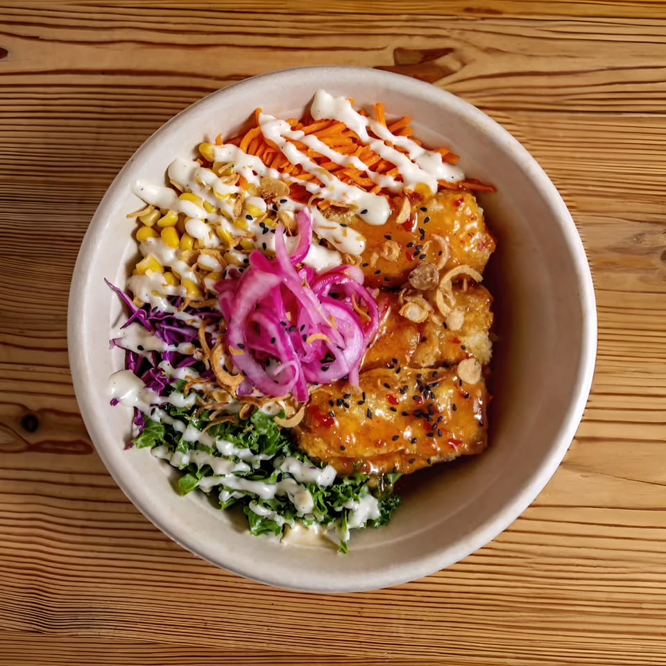 Bao by Kaya's Asian-fusion bowl with crispy chicken, pickled onions, corn, carrots, and greens.